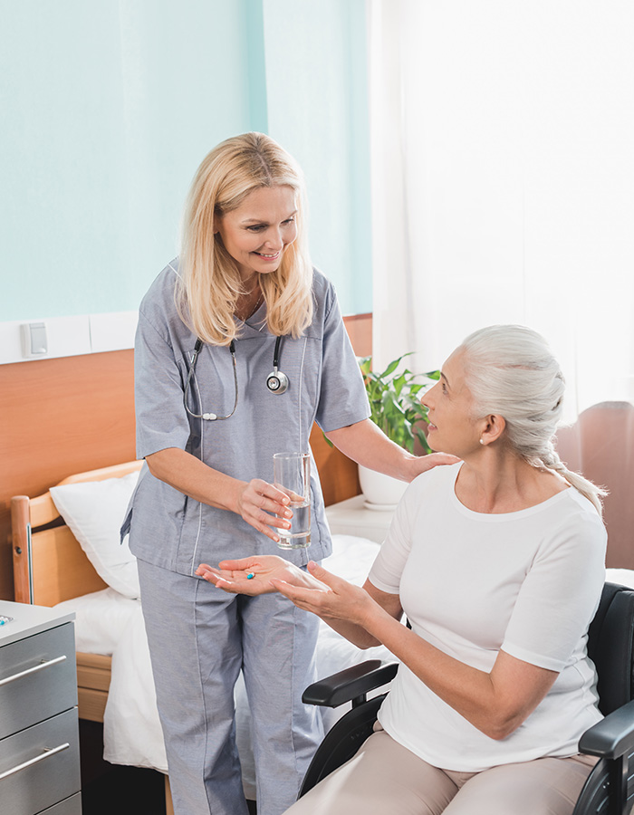 smiling-nurse-giving-glass-of-water-to-disabled-se-4JDRBJR.jpg